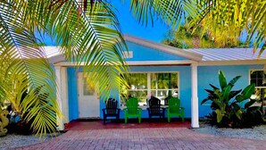 A house with a blue exterior, a brick driveway, and green chairs outside. - VILLA 6 ·Pool     1 King  1 Queen.   Daily rentals (Sarasota)