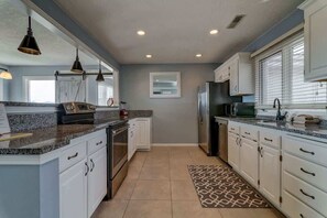 A modern kitchen with granite countertops, stainless steel appliances, and pendant lighting.