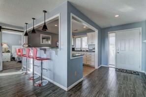 A modern kitchen with bar stools, a dining area with a table and chairs, and a separate dining room with a window. - Las Palmas Resort #411 | All-Inclusive Amenities (Saint George)