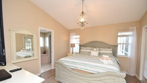 Une chambre à coucher avec un lit, un miroir, un lustre et une fenêtre.