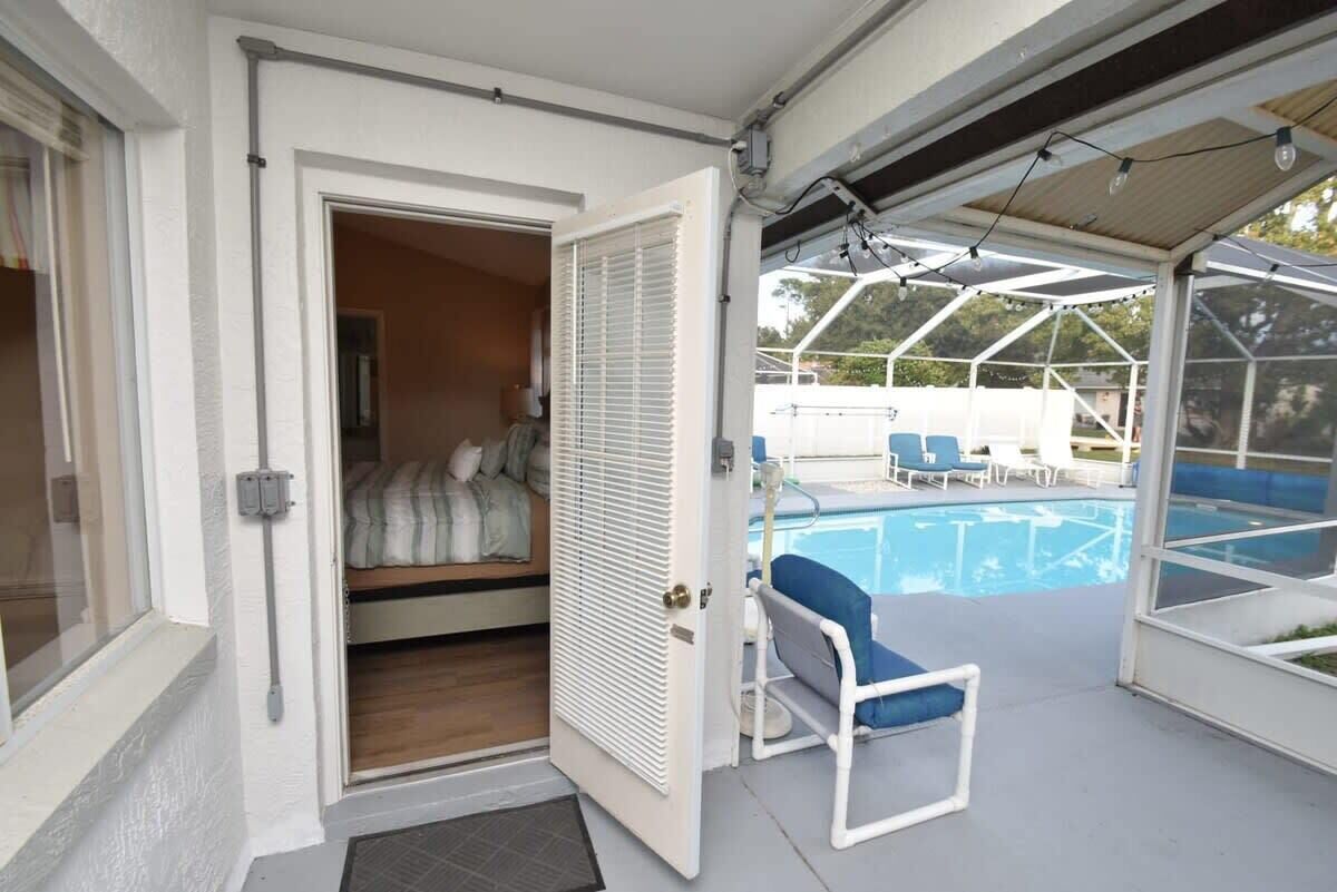 Ein überdachter Außenbereich mit Pool, eine Tür zu einem Zimmer mit einem Bett und einem Stuhl.