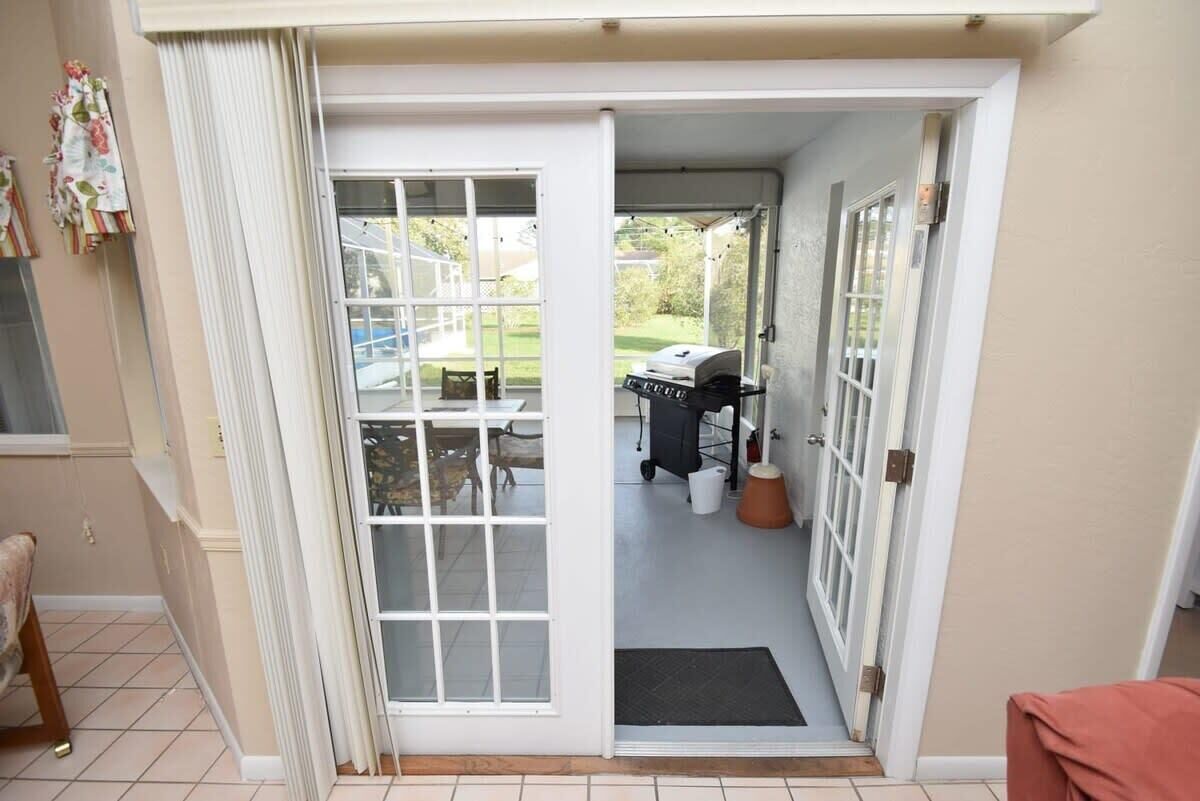 A sliding glass door leading to an outdoor patio area with a grill and a table.