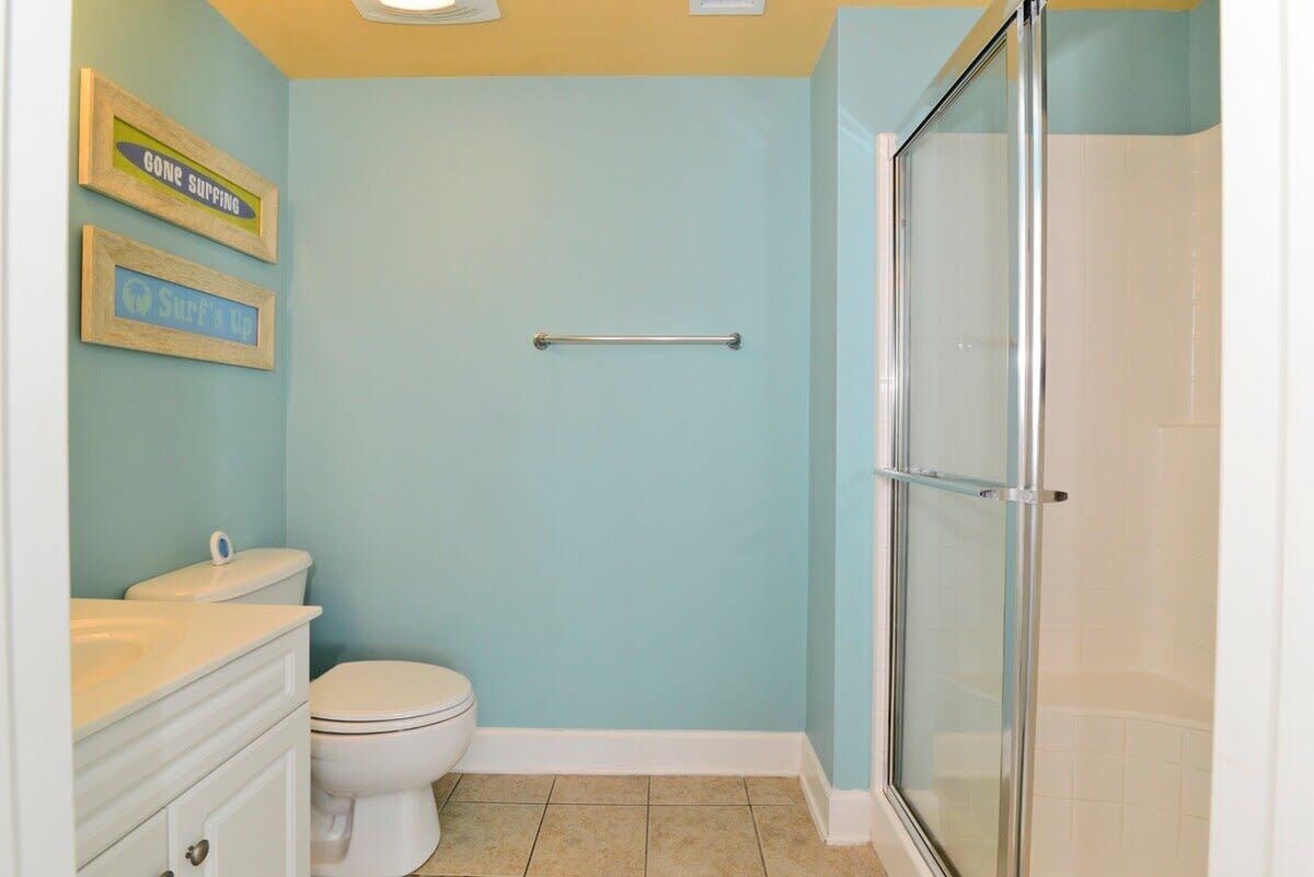A bathroom with a toilet, a vanity with a sink, and a glass shower enclosure.