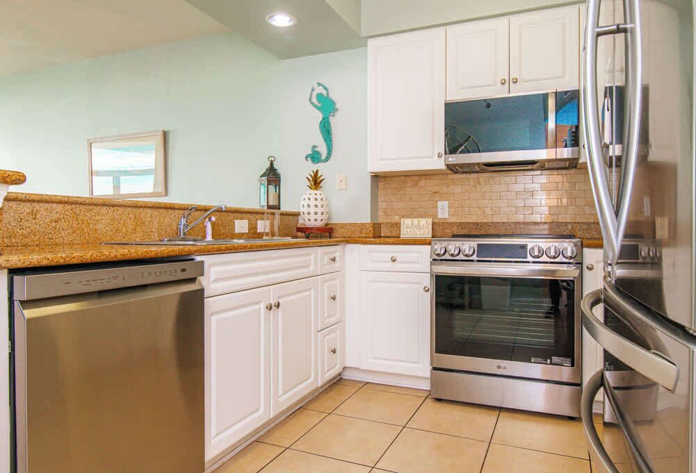 A kitchen with white cabinets, a stainless steel dishwasher, an oven, and a microwave.