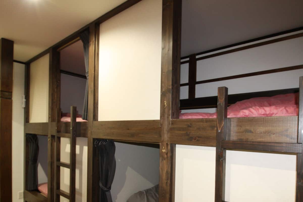 A bunk bed room with wooden frames and white mattresses.