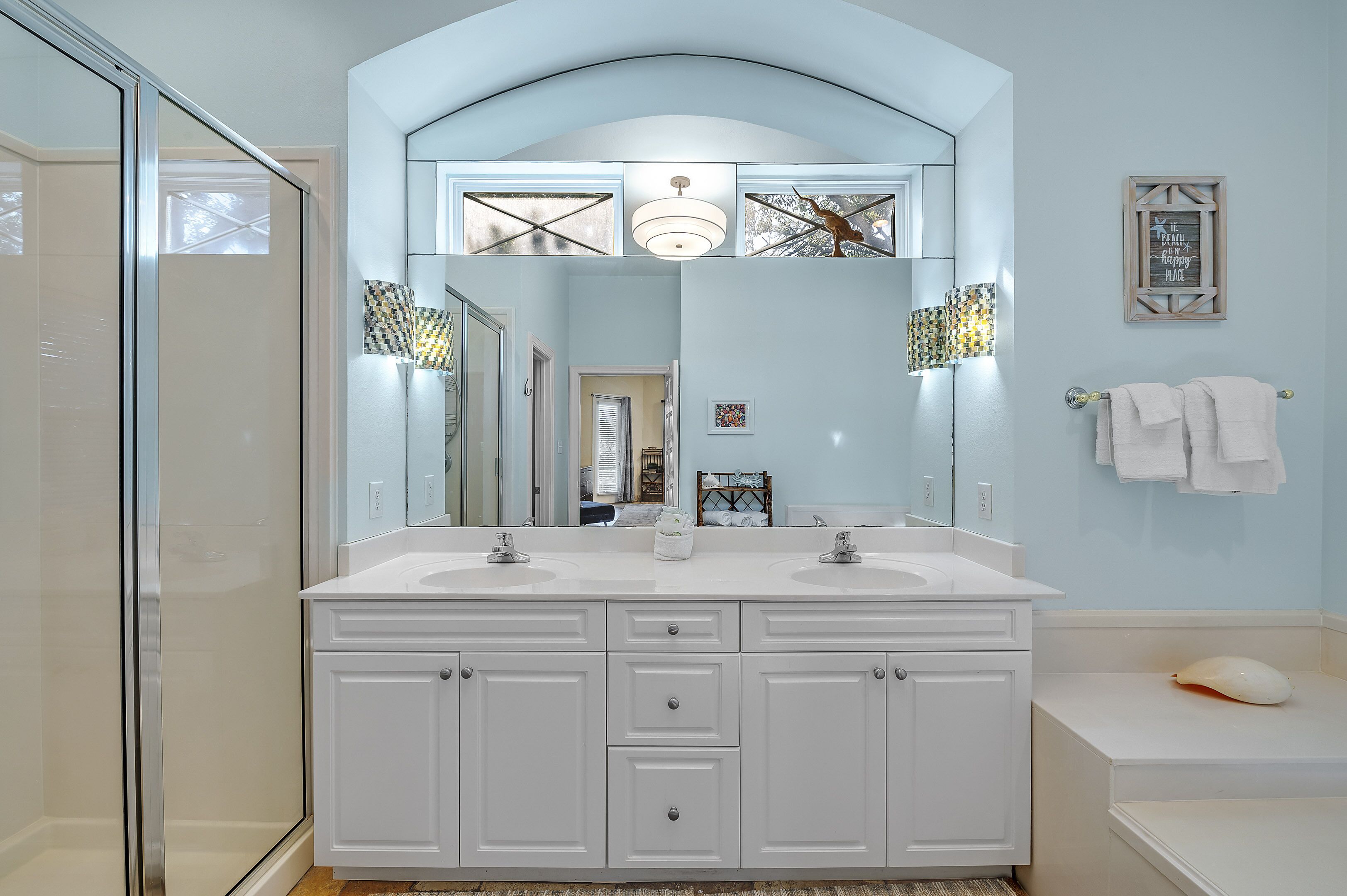 A bathroom with a large mirror, two sinks, and a bathtub.