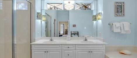 A bathroom with a large mirror, two sinks, and a bathtub.
