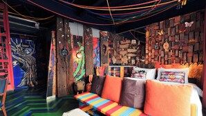 A vibrant room with a colorful striped sofa, a wooden wall with various decorations, and a unique ceiling design. - MeStyle Garage Hotel (Bangkok)