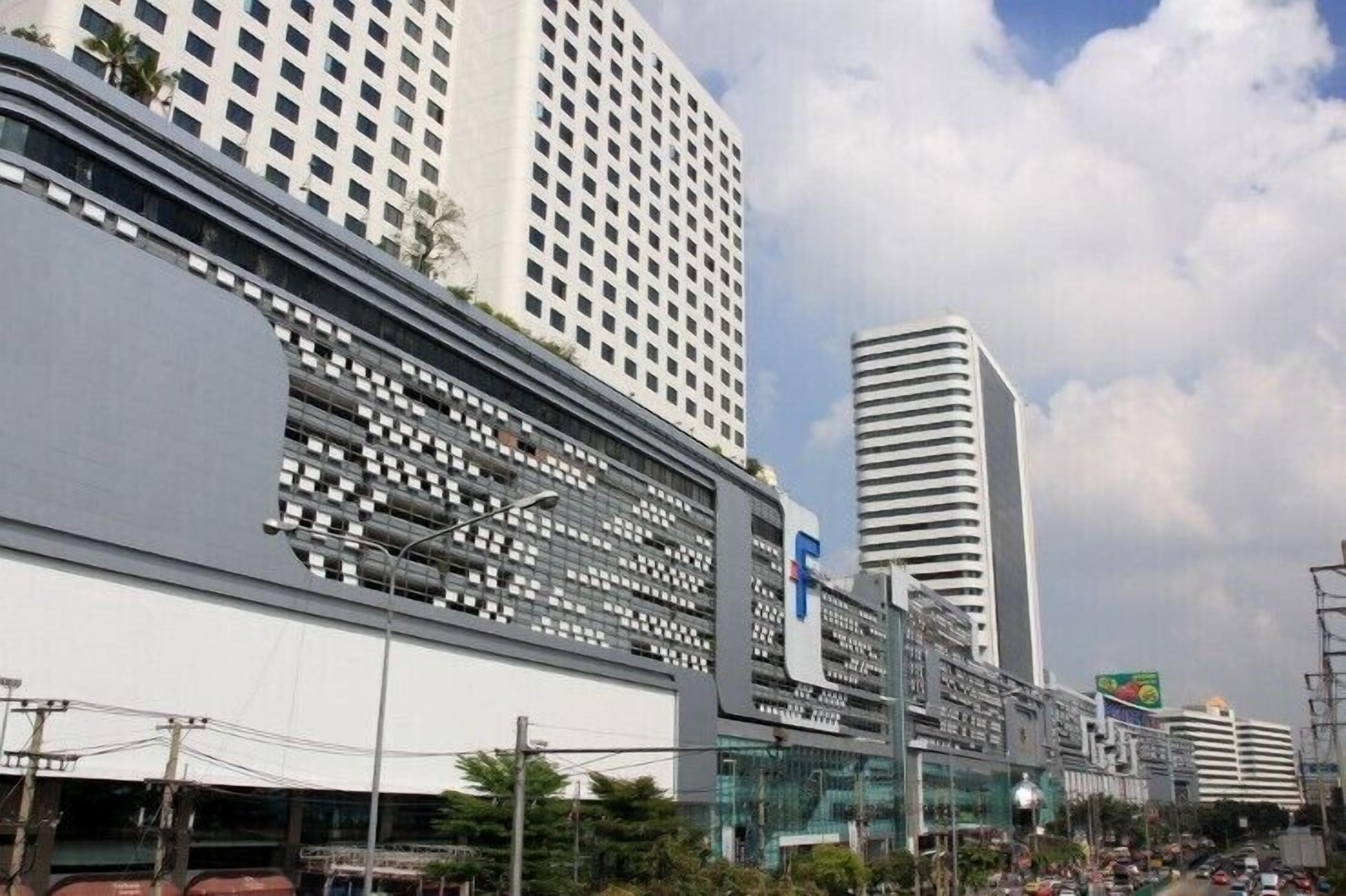 A modern urban street with high-rise buildings, including a prominent white building with a grid-like facade and a tall building with horizontal lines.