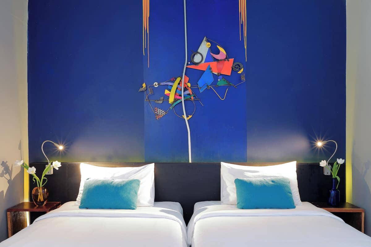 A hotel room with a large bed, two nightstands, and a wall art piece.