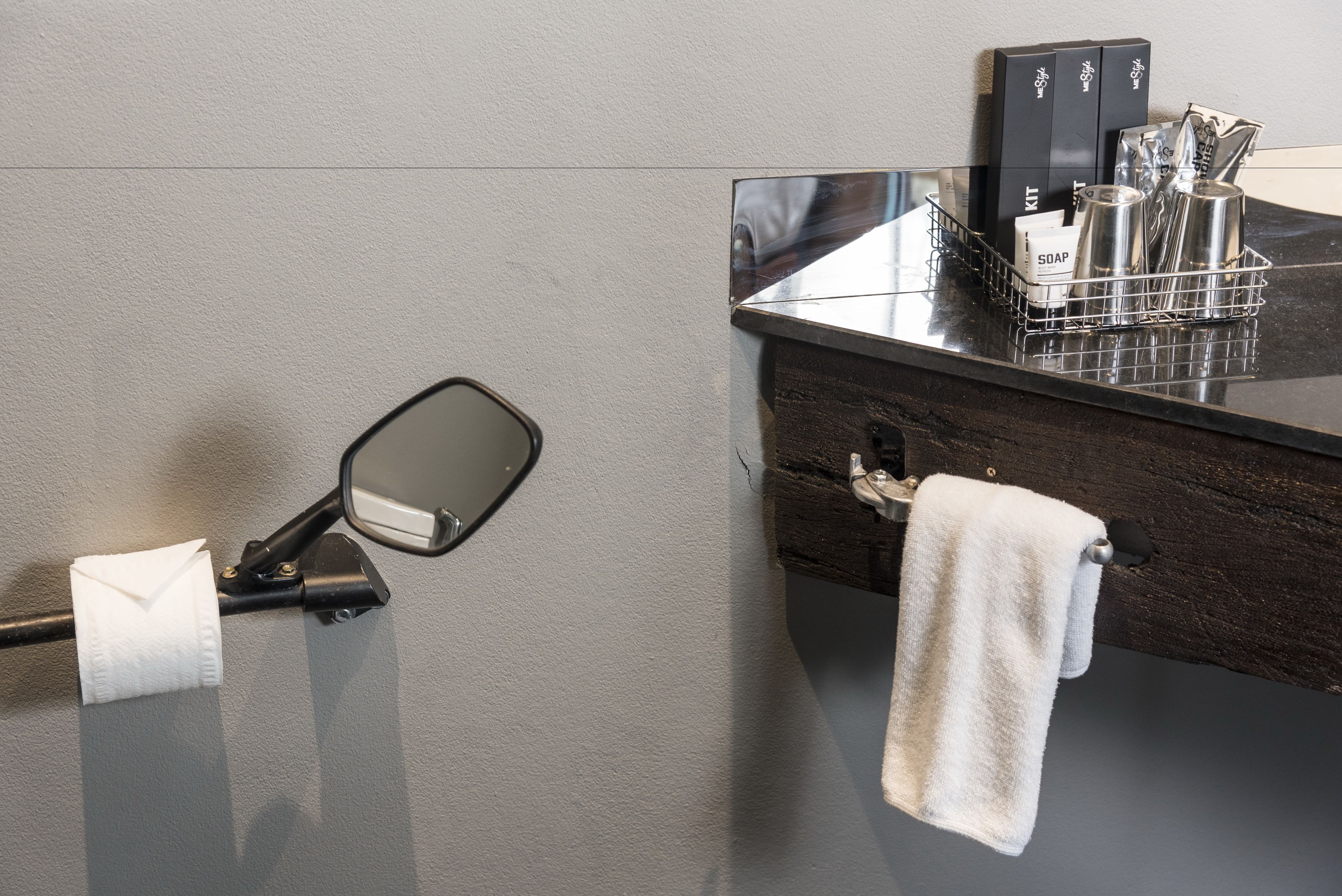 A bathroom with a towel rack, a mirror, a soap dispenser, and a sink.