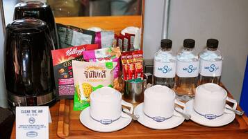 A tray with coffee makers, coffee packets, bottled water, and cups.