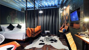 A modern hotel room with a bed, a desk, a chair, a cowhide rug, and a television. - MeStyle Garage Hotel (Bangkok)
