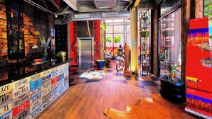 A modern interior with a checkered floor, a bar area with license plates, and a colorful wall art piece. - MeStyle Garage Hotel (Bangkok)