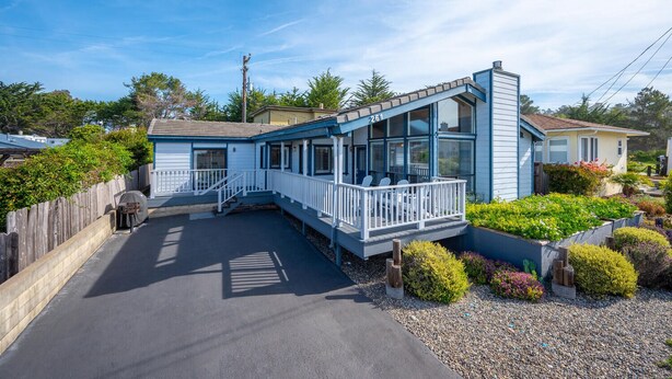 A two-story house with a covered porch, a small garden, and a paved driveway. - Beautiful Moonstone Beach Rental Just Steps Away From the Boardwalk! (Cambria)