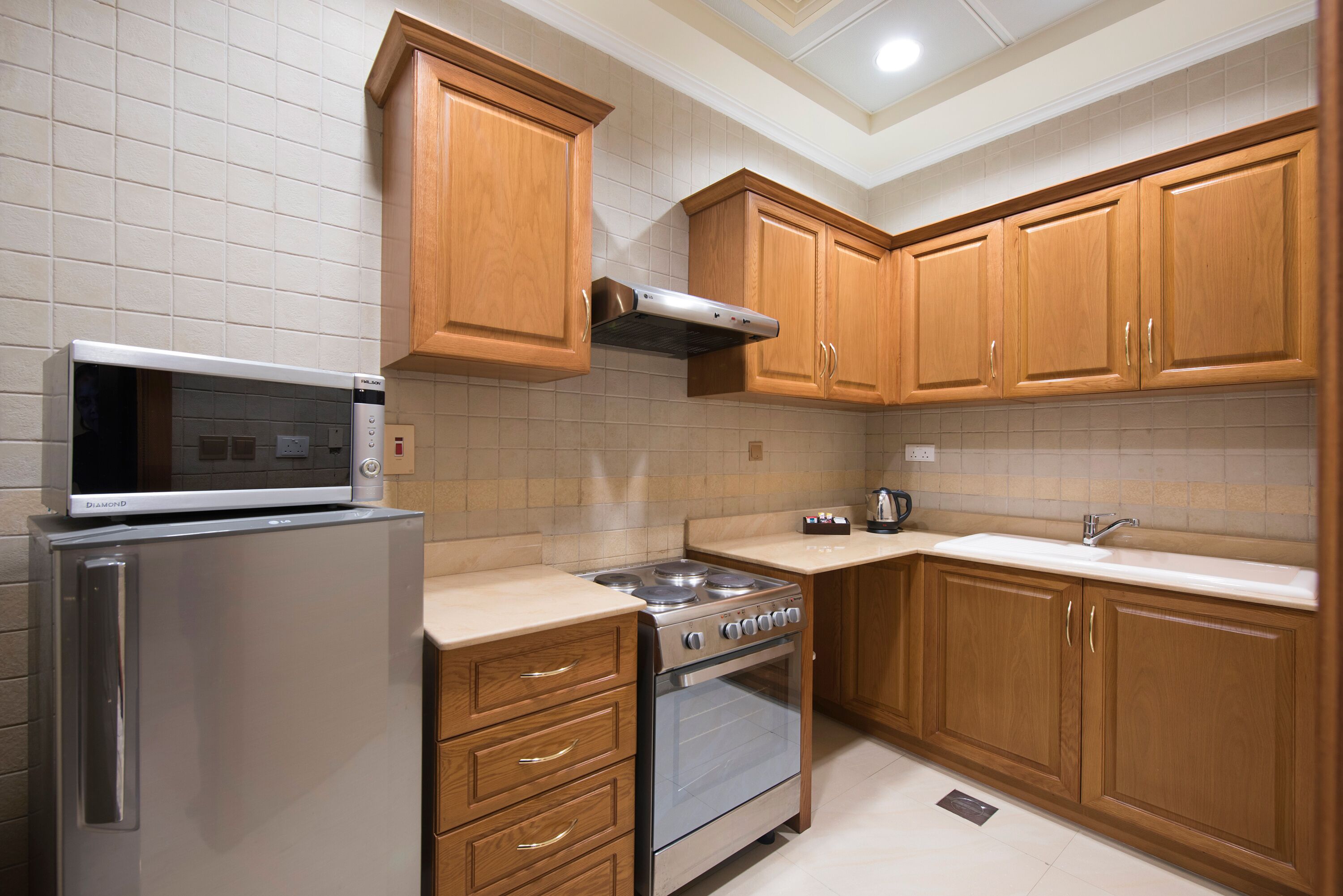A kitchen with wooden cabinets, a stainless steel refrigerator, a microwave, and an oven.