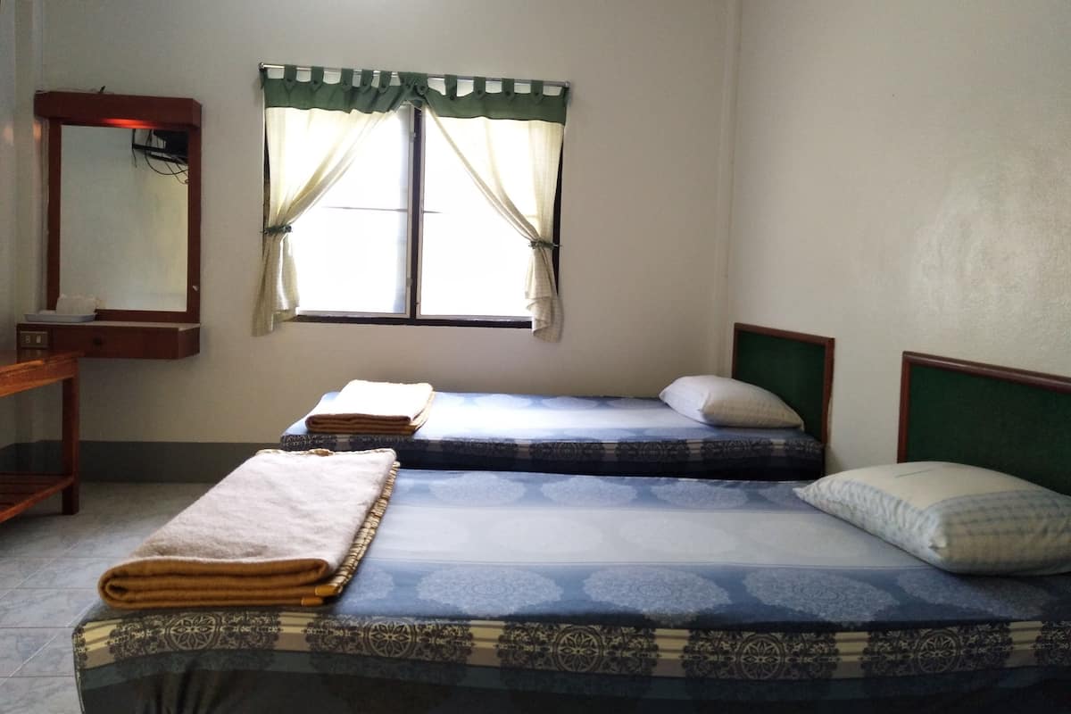 Une chambre avec deux lits, un miroir et une fenêtre avec des rideaux.
