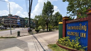 A hotel entrance with a blue sign, a road with cars, and a traffic light.