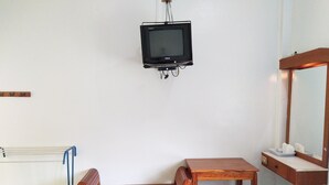 A small room with a wooden bench, a small table, a wall-mounted television, and a mirror.