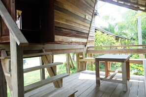 Une terrasse en bois, agrémentée de bancs et d’une table, entourée d’une végétation luxuriante.