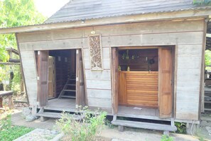 Un bâtiment rustique en bois, doté de deux portes en bois ouvertes et d’un petit espace porche.