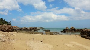 A beach with rocky outcrops and a clear sky. - Uminosoba Pension (Ginoza)