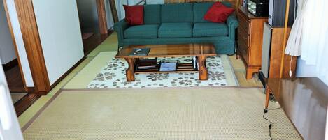 A living room with a green sofa, wooden coffee table, and a TV stand.