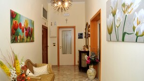 A hallway with a sofa, a vase of flowers, and two paintings. - B&B A Due Passi (Otranto)