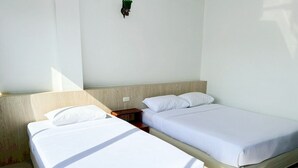 Een kamer met twee bedden, een houten hoofdbord, een nachtkastje en een wandlamp.