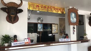 Een receptiebalie met een stierenhoofd decoratie, een klok en een lijst met een portret erboven.