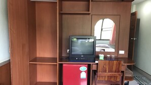 Een knus kamertje met een houten bureau, een kleine rode koelkast en een stoel.