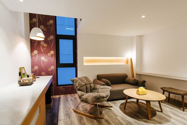 A modern living room with a sofa, a rocking chair, a wooden coffee table, and a small side table. - CHECK inn Taichung Zhongshan (Taichung)