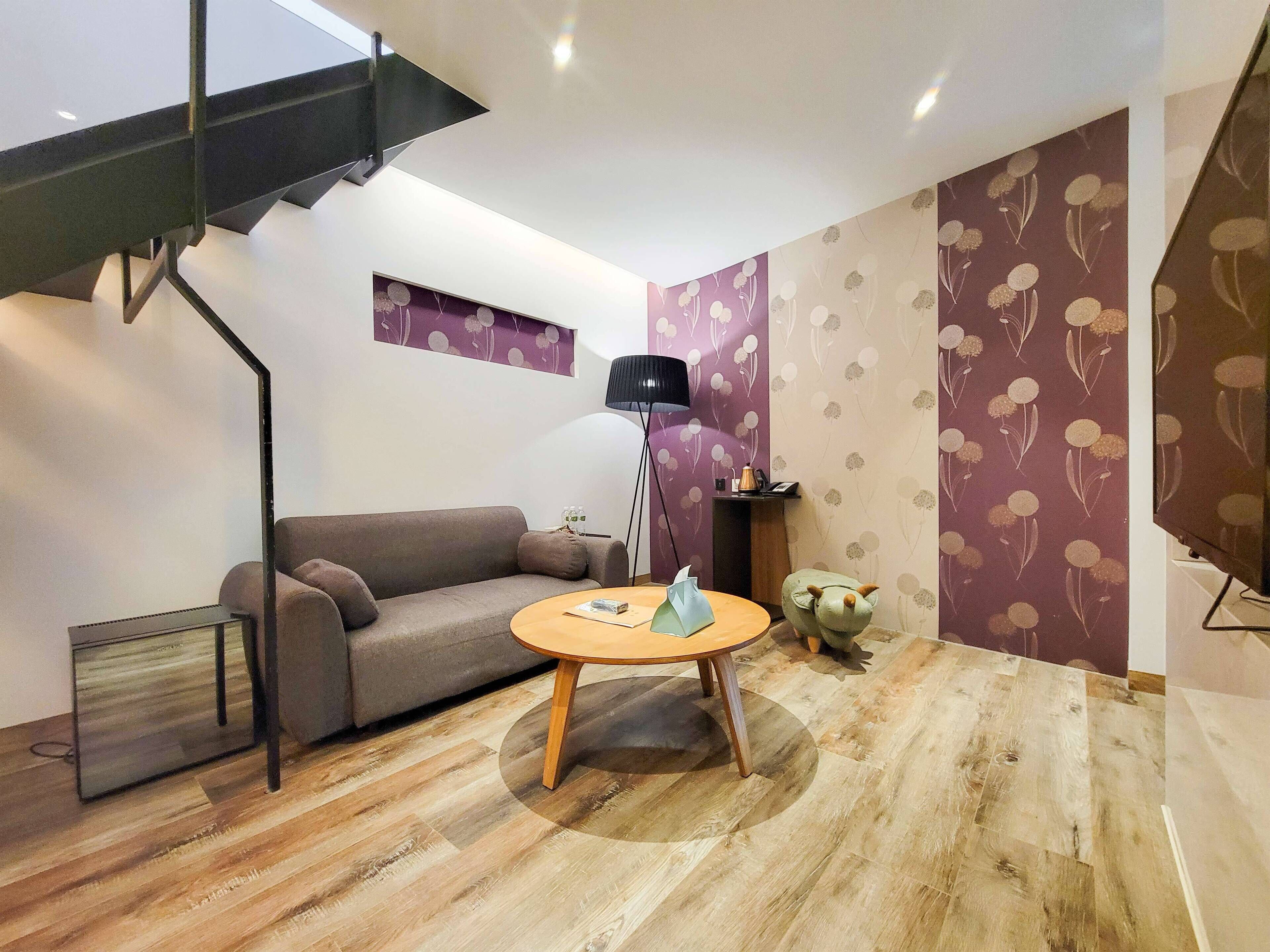 Un salon moderne avec un canapé gris, une table basse ronde en bois et un lampadaire noir.