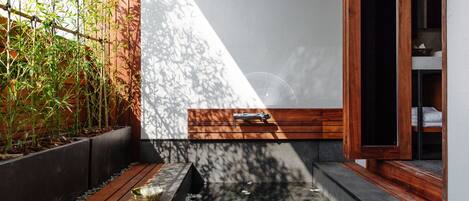 A modern outdoor space with a wooden deck, a small water feature, and a bamboo garden.