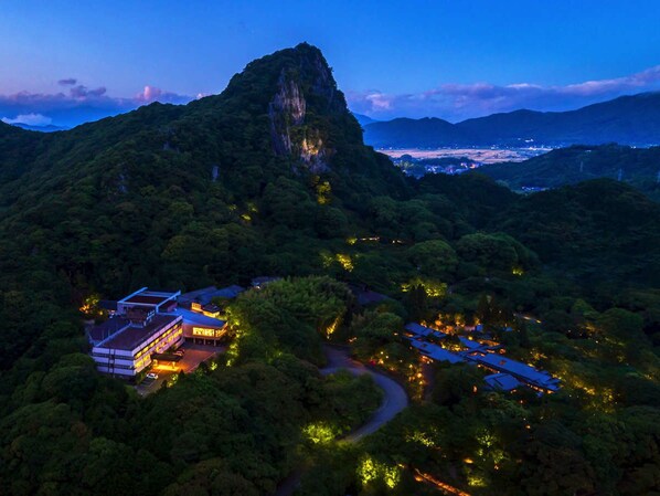 An aerial view of a resort with a prominent mountain peak, multiple buildings, and a winding road.