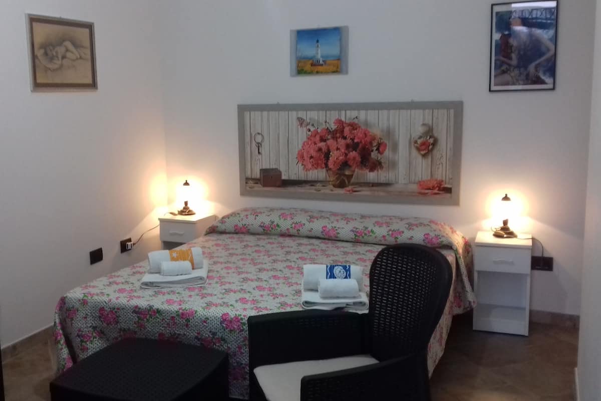 Ein Schlafzimmer mit einem Bett, zwei Nachttischen, einem Sessel und einer Lampe.