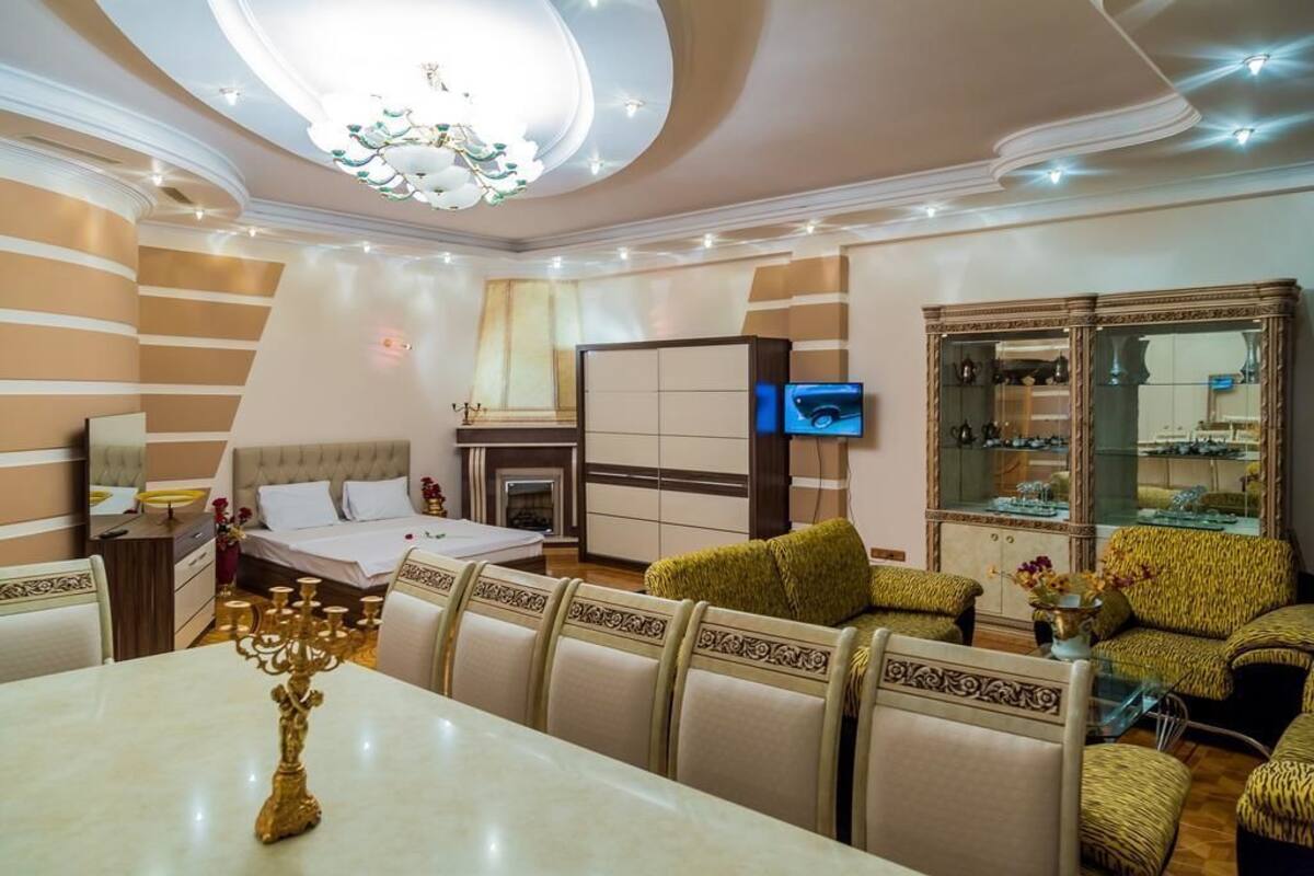 Une chambre d’hôtel comprenant un lit, une table à manger avec un chandelier, un canapé et un meuble avec des portes en verre.