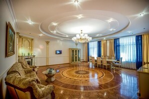 A spacious living room with a large wooden floor, a chandelier, a sofa, and a dining area. - La Villa Hotel (Baku)