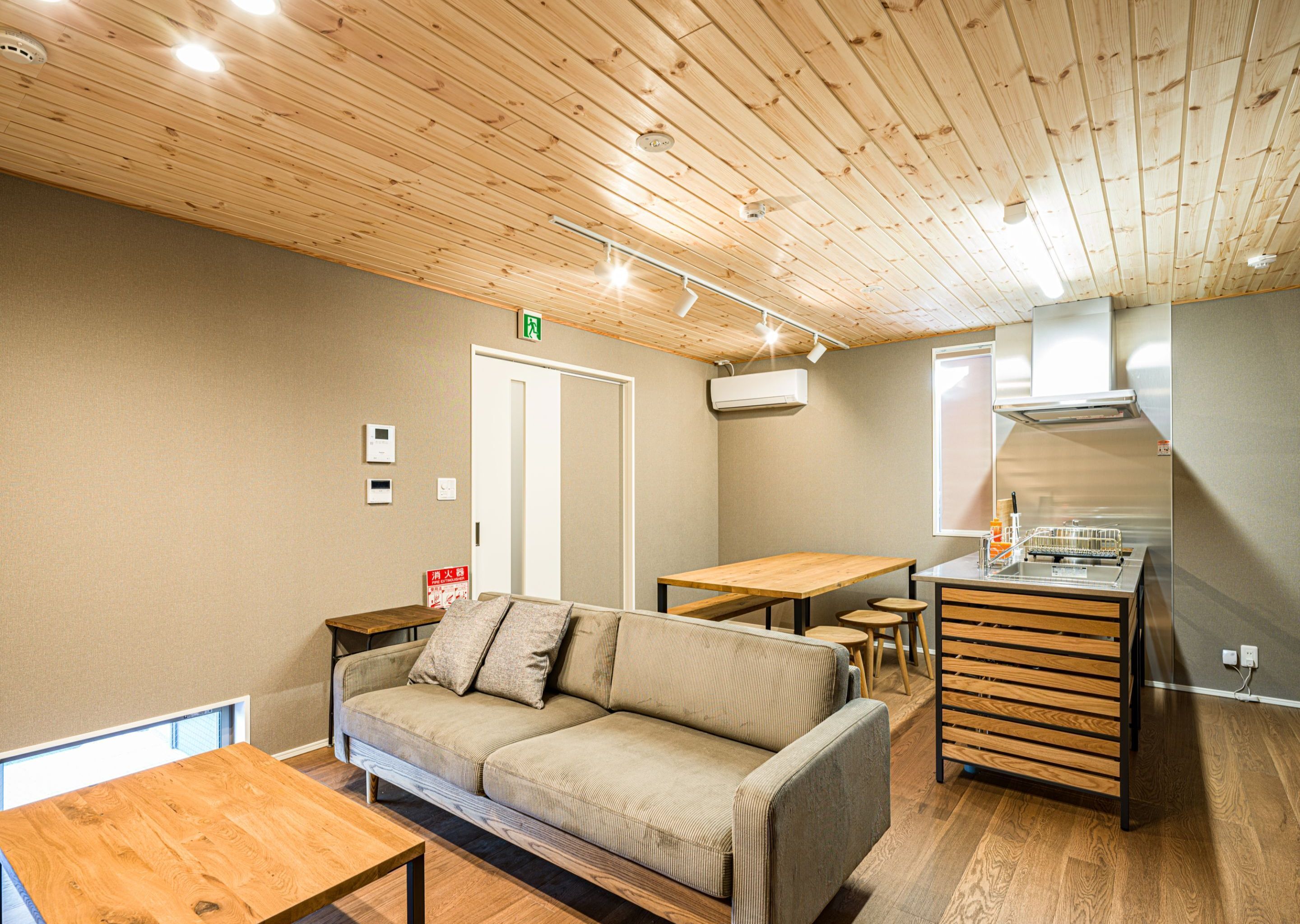 Un interior moderno con techo de madera, un sofá, una mesa de comedor y una kitchenette.