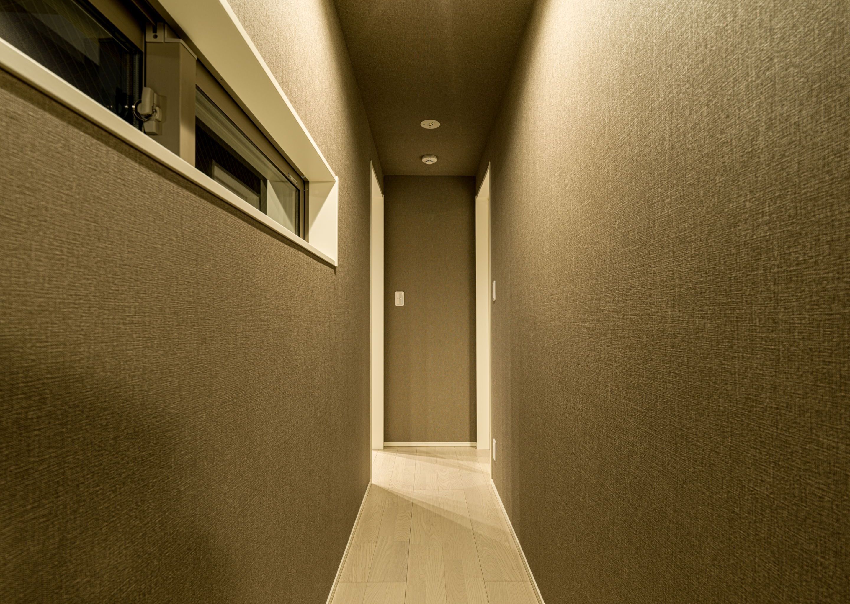 A narrow hallway with textured walls and a wooden floor.