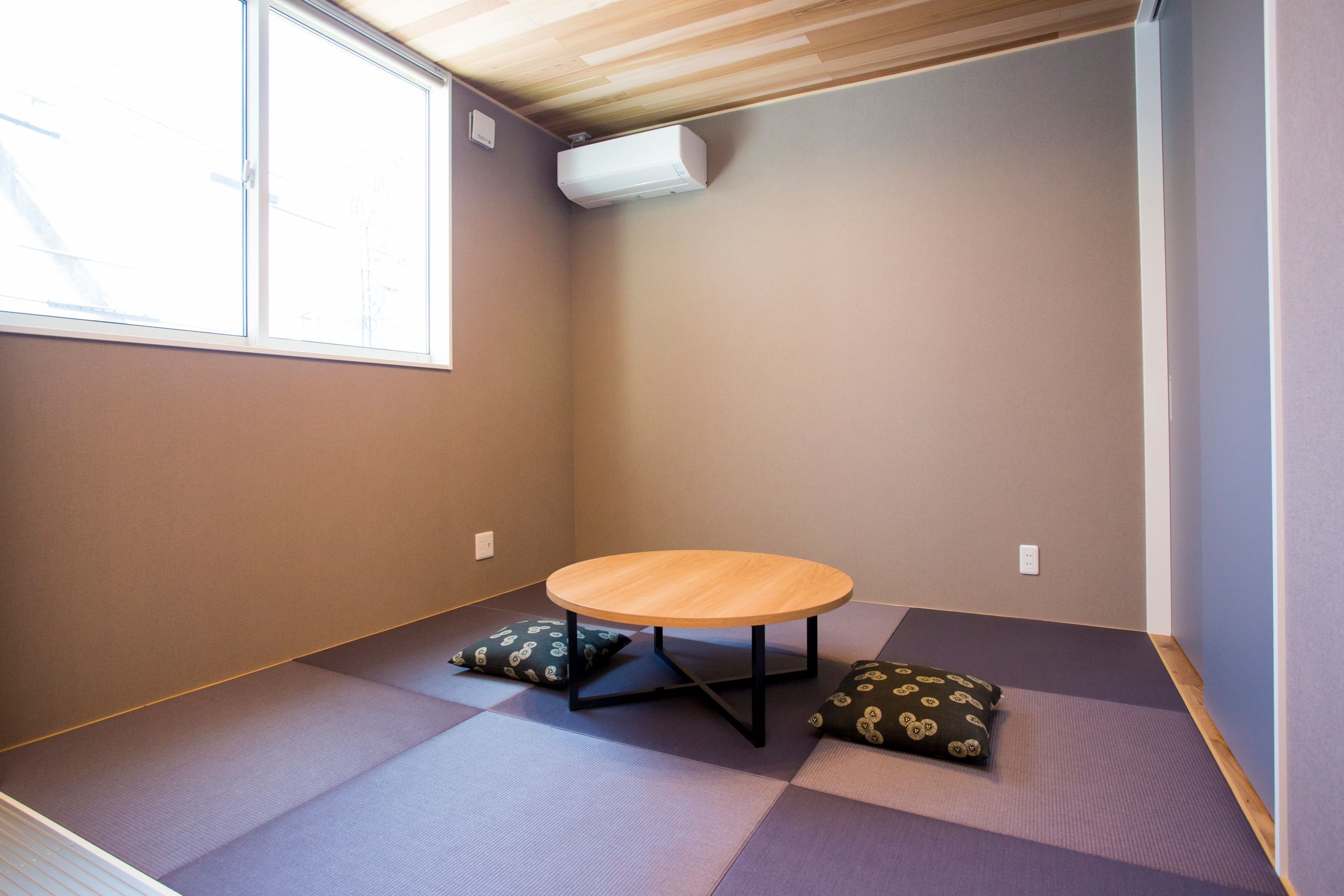 A room with tatami mats, a round table, and cushions.