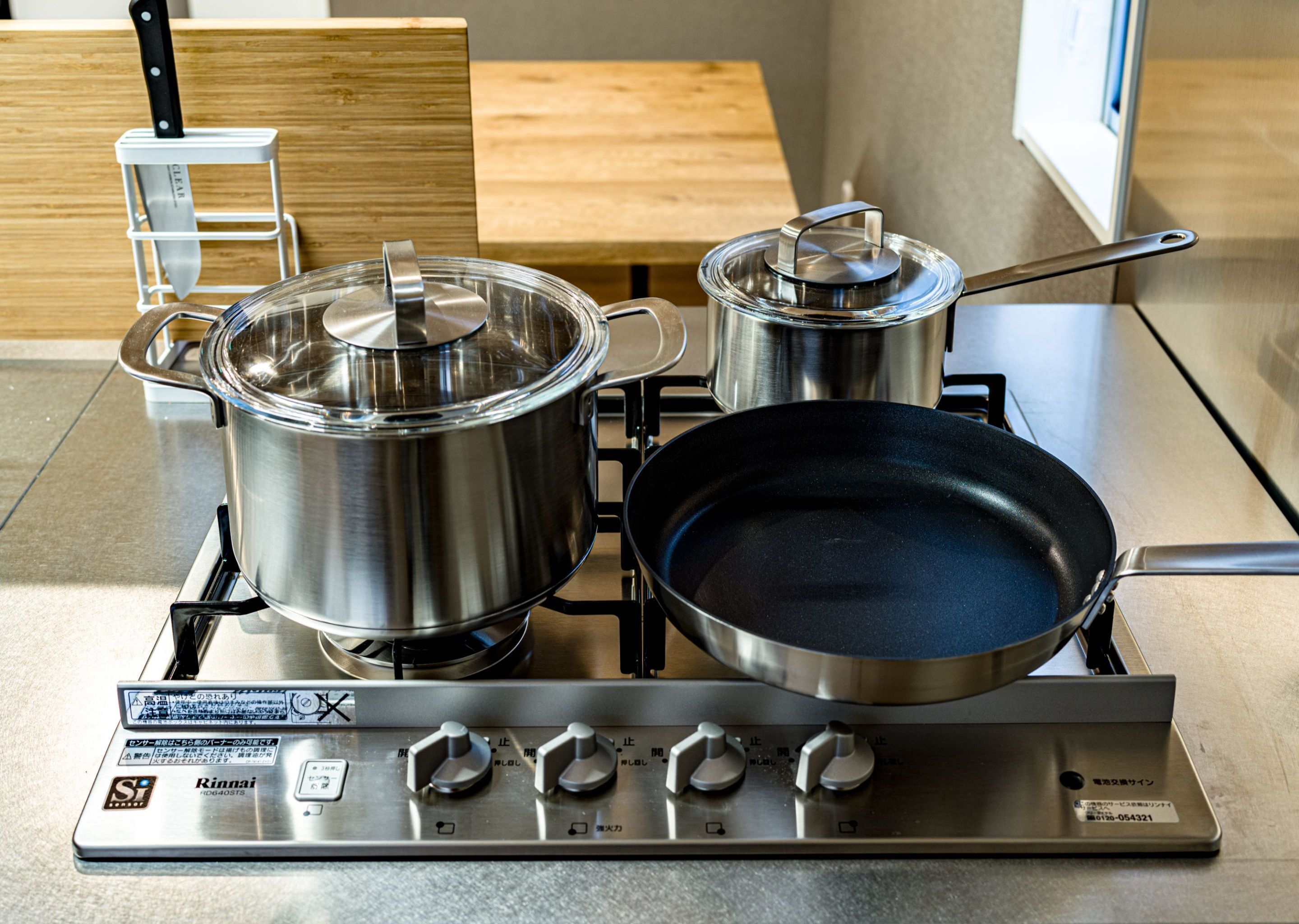 A kitchen with stainless steel appliances, including a stove, pots, and a frying pan.