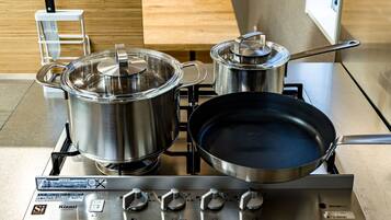 A kitchen with stainless steel appliances, including a stove, pots, and a frying pan.
