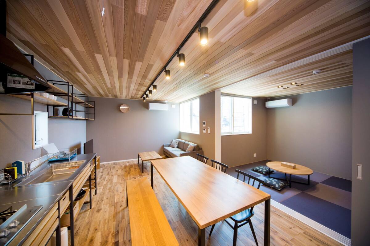 Una cocina moderna con piso de madera, una encimera larga y estanterías empotradas.