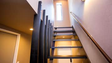 A modern staircase with a metal railing, a door at the bottom, and a window at the top.