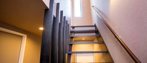 Un escalier moderne avec une rampe en métal, une porte en bas et une fenêtre en haut.