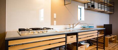 A modern kitchen with a central island, built-in appliances, and wooden shelving.