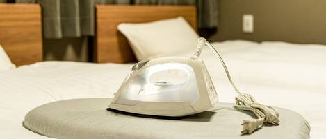 A bed with a white iron and a grey pillow.