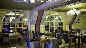A restaurant with a classic interior, featuring arched windows, chandeliers, and striped upholstered chairs. - Grand Opera Hotel (Almaty)