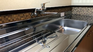 Eine Küche mit Spüle aus Edelstahl, einem Wasserhahn und einer gefliesten Rückwand.